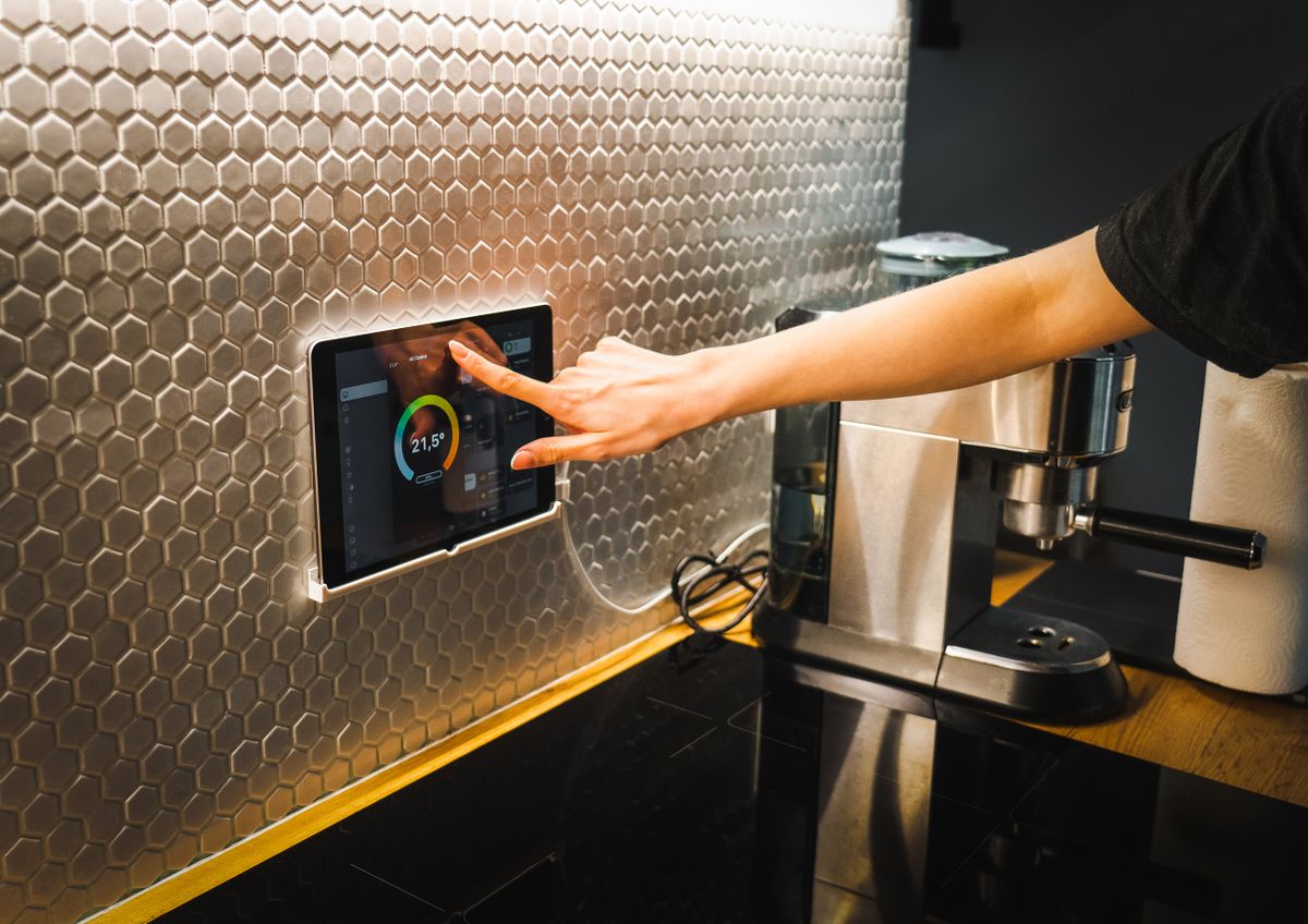 Persona controlando su casa inteligente desde una tablet en la cocina